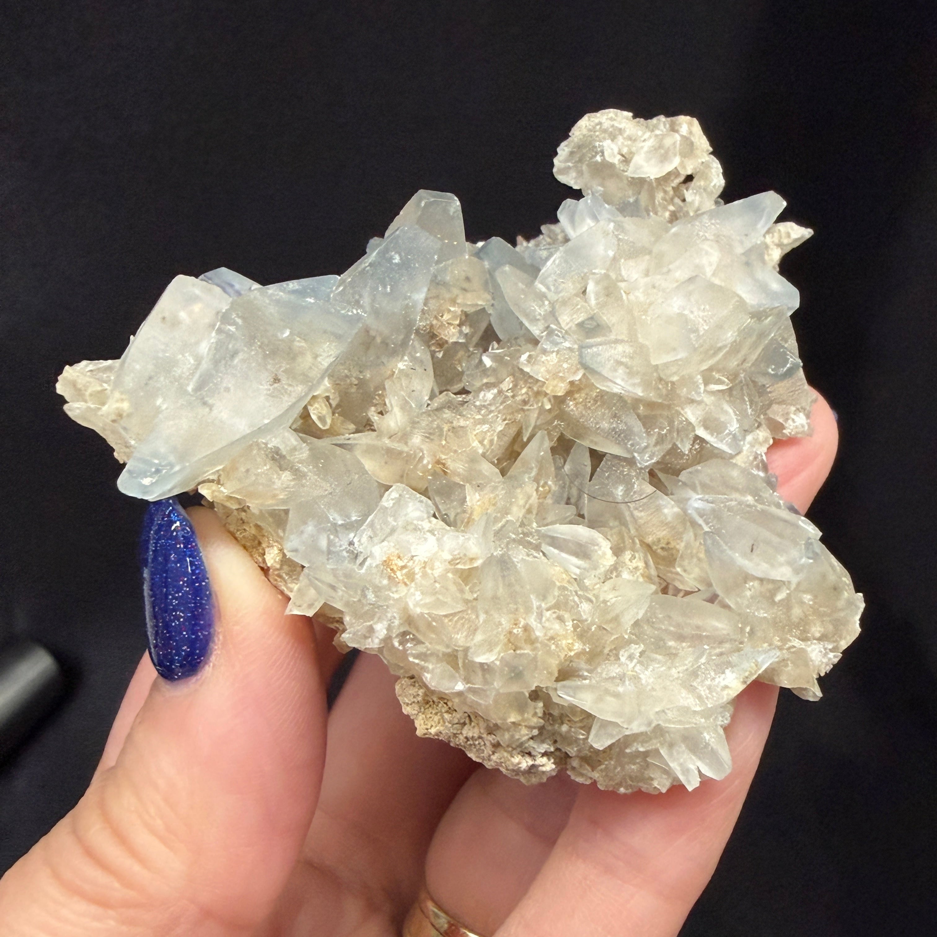 Hand holding a crystal cluster against a black background