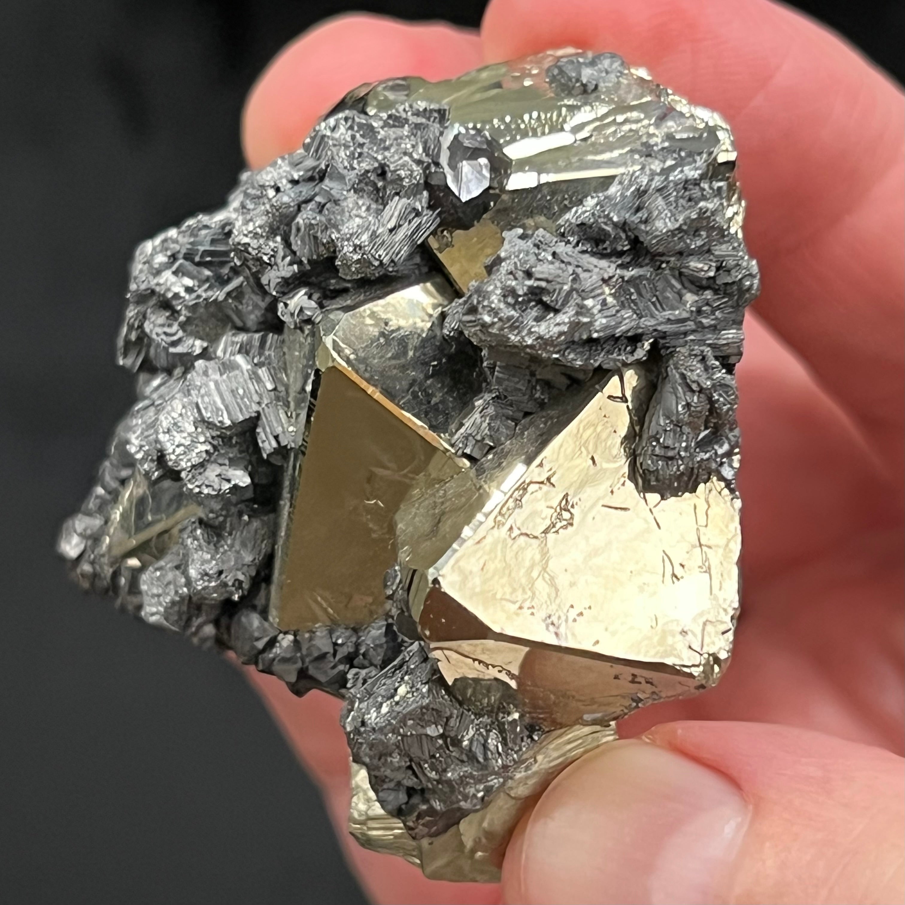 The faces of some of the well formed octahedral Pyrite crystals show etched, maze looking polycrystalline growth. The faces are otherwise smooth and brightly reflective.