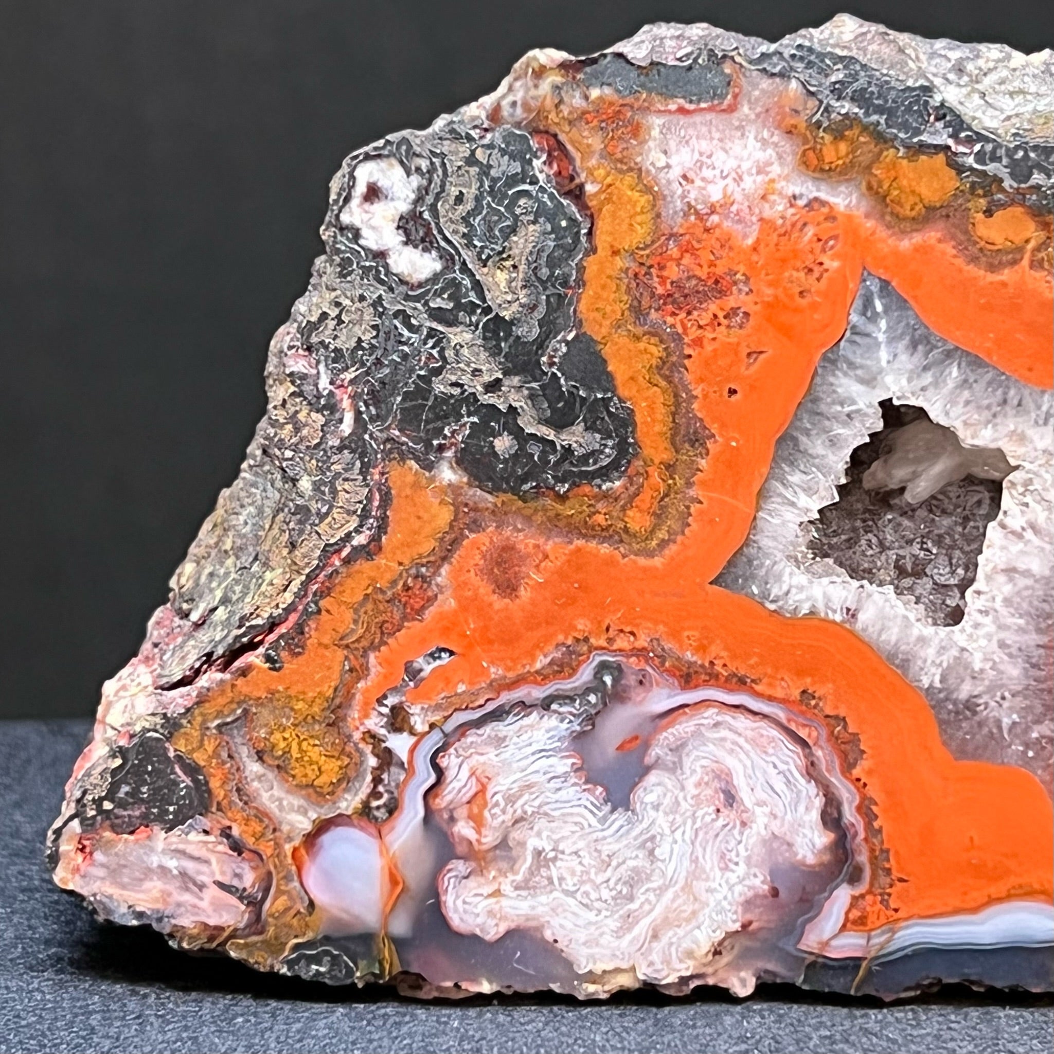 Some of the beautiful features of this sensational Moroccan Agate include eye popping bright red banding and swirling white layered formations., The hematite structures in this agate present with a metallic gleam when the specimen is turned in the light.