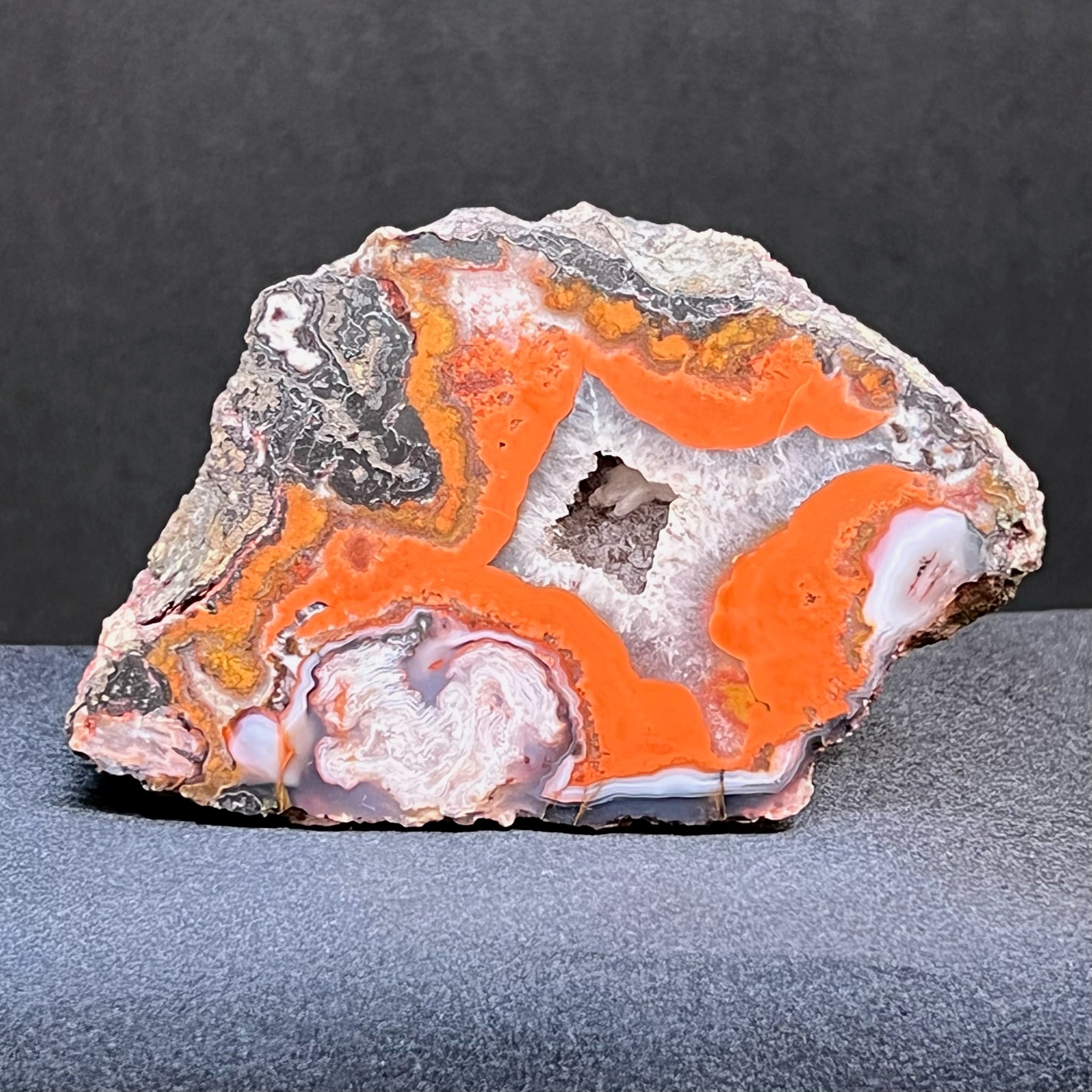 The bright red flowing banding in this Moroccan Agate provides a striking contrast to the white formations and the quartz crystalline pocket.