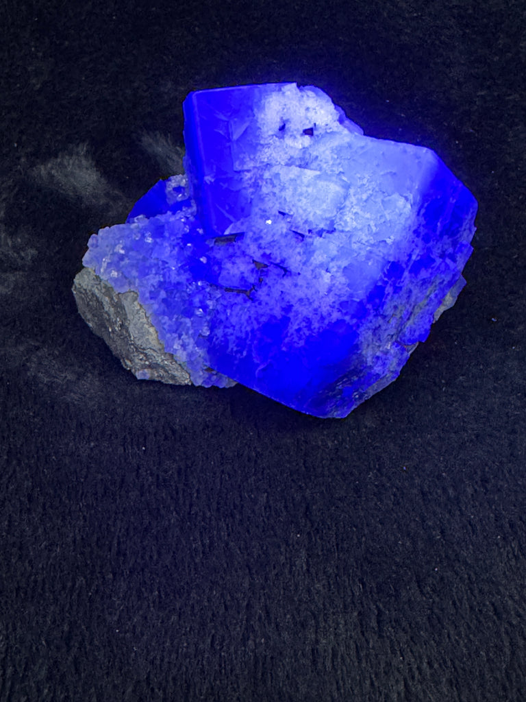 The color change of Milky Way Fluorite is incredible between indoor and outdoor lighting. Indoor lighting it may present as black or almost dark green with white dusting. Under UV light it fluoresces a bright lilac and in natural daylight it turns to a stunning dark blue / purple color.