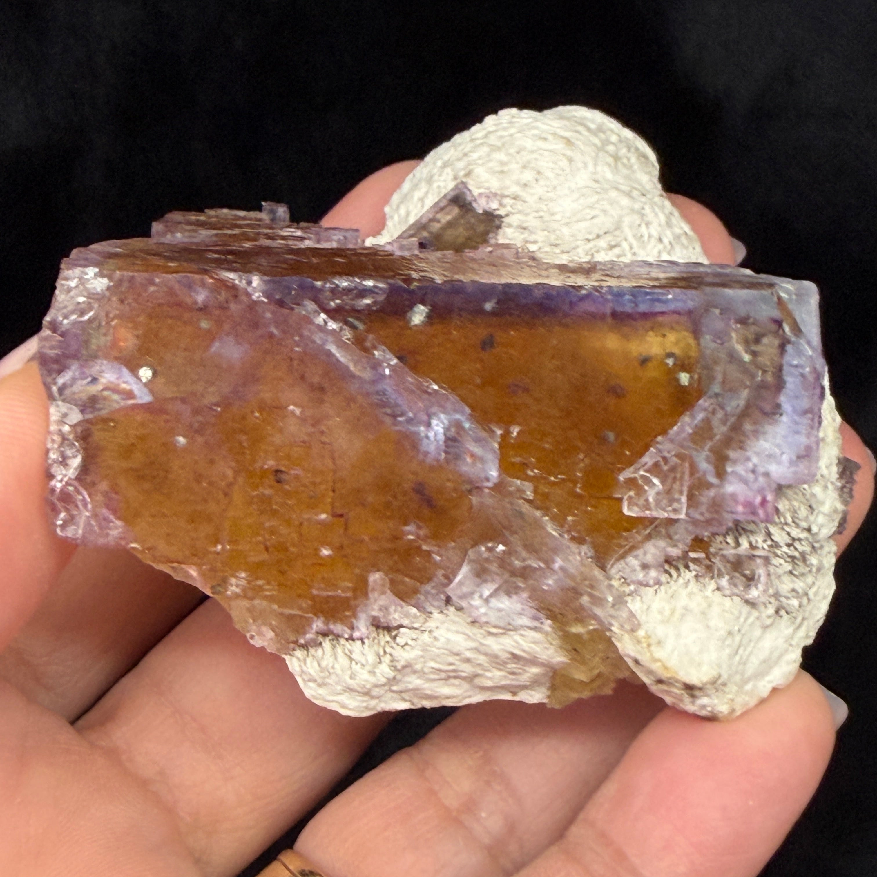 Hand holding a Fluorite crystal with visible color variations