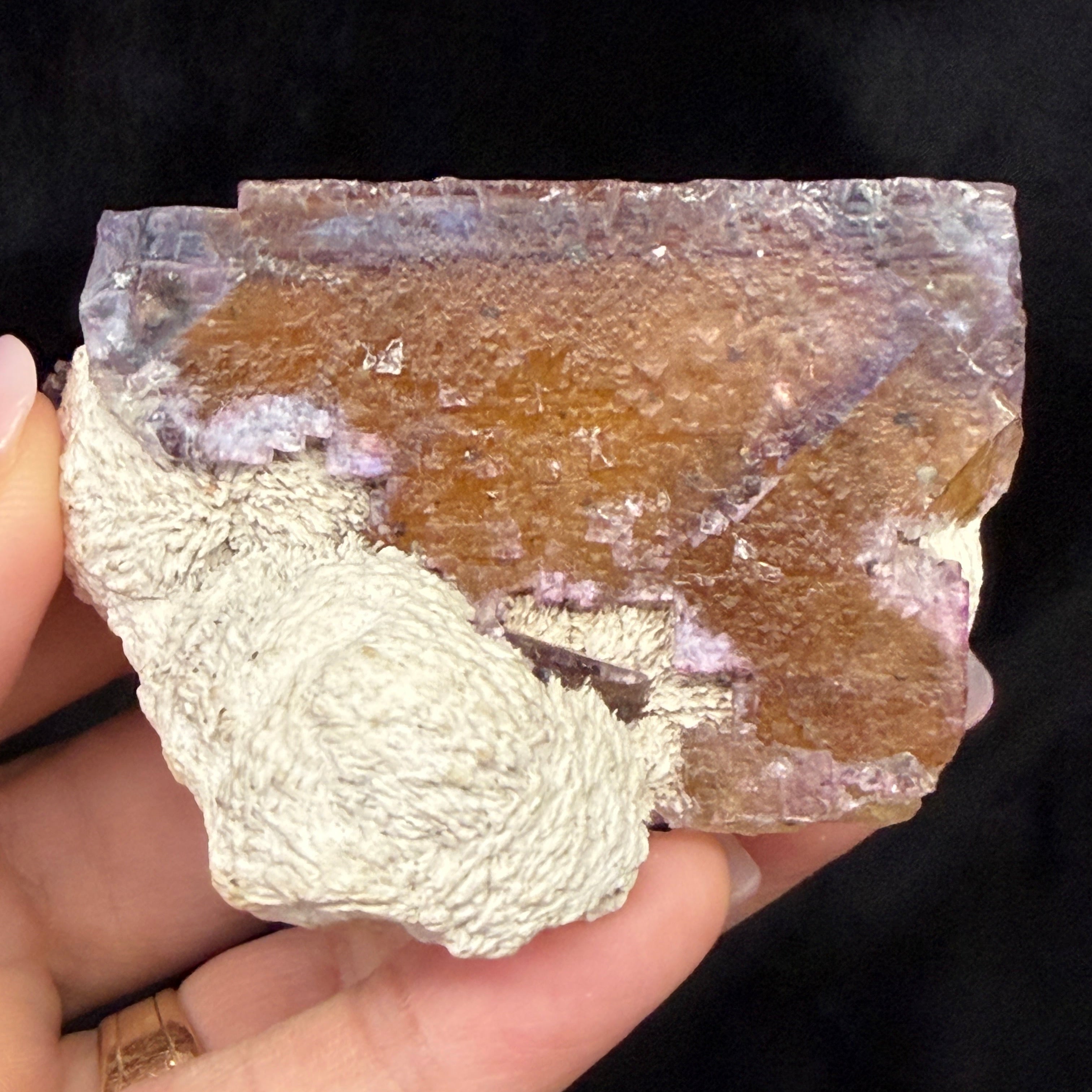 Hand holding Fluorite against black background