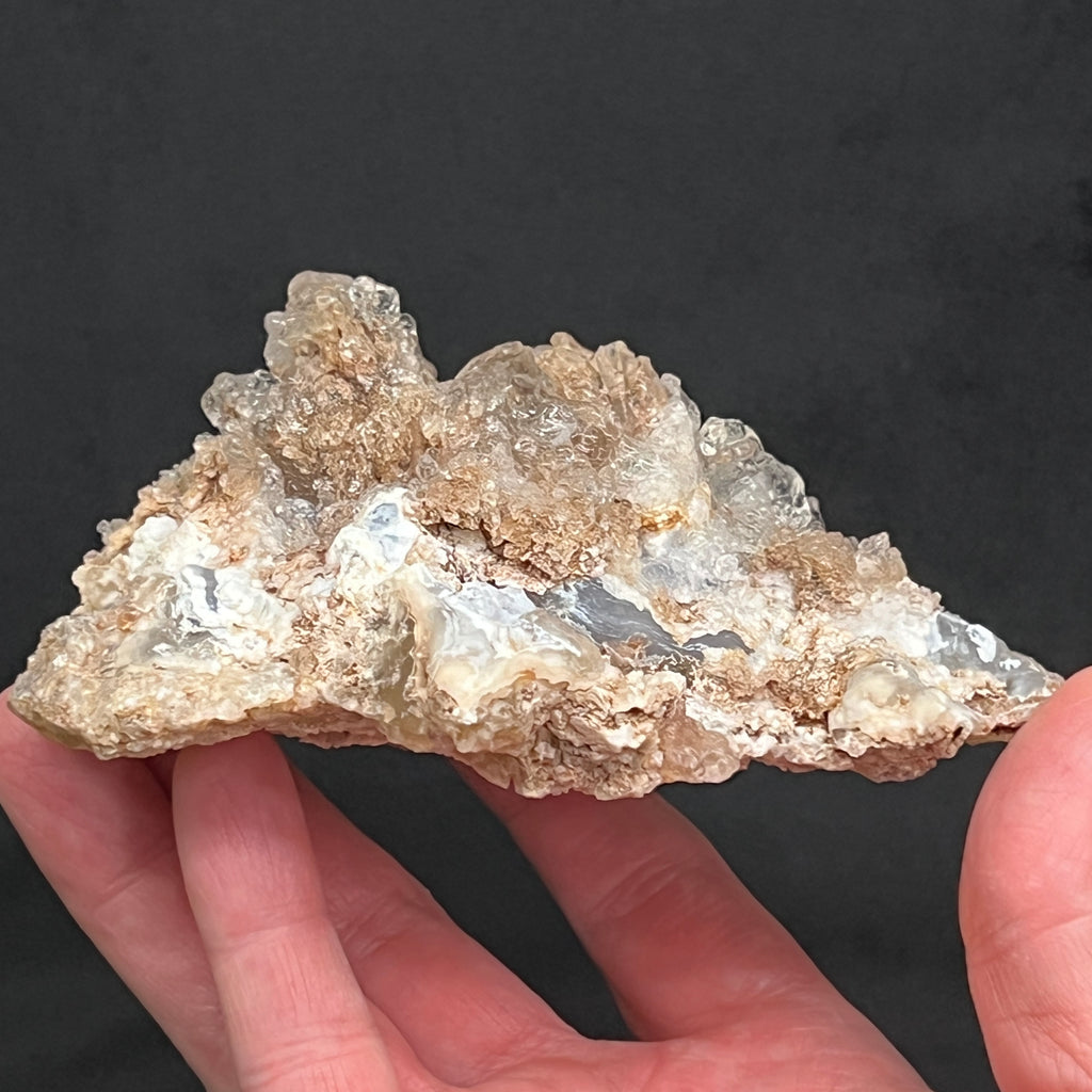 With highest respect to protecting and presenting the natural state of the crystals, it is normal that there remains small amounts of sediment or Rhyolite tuff trapped within and in between the Hyalite spherules. This is truly an excellent example of the species!