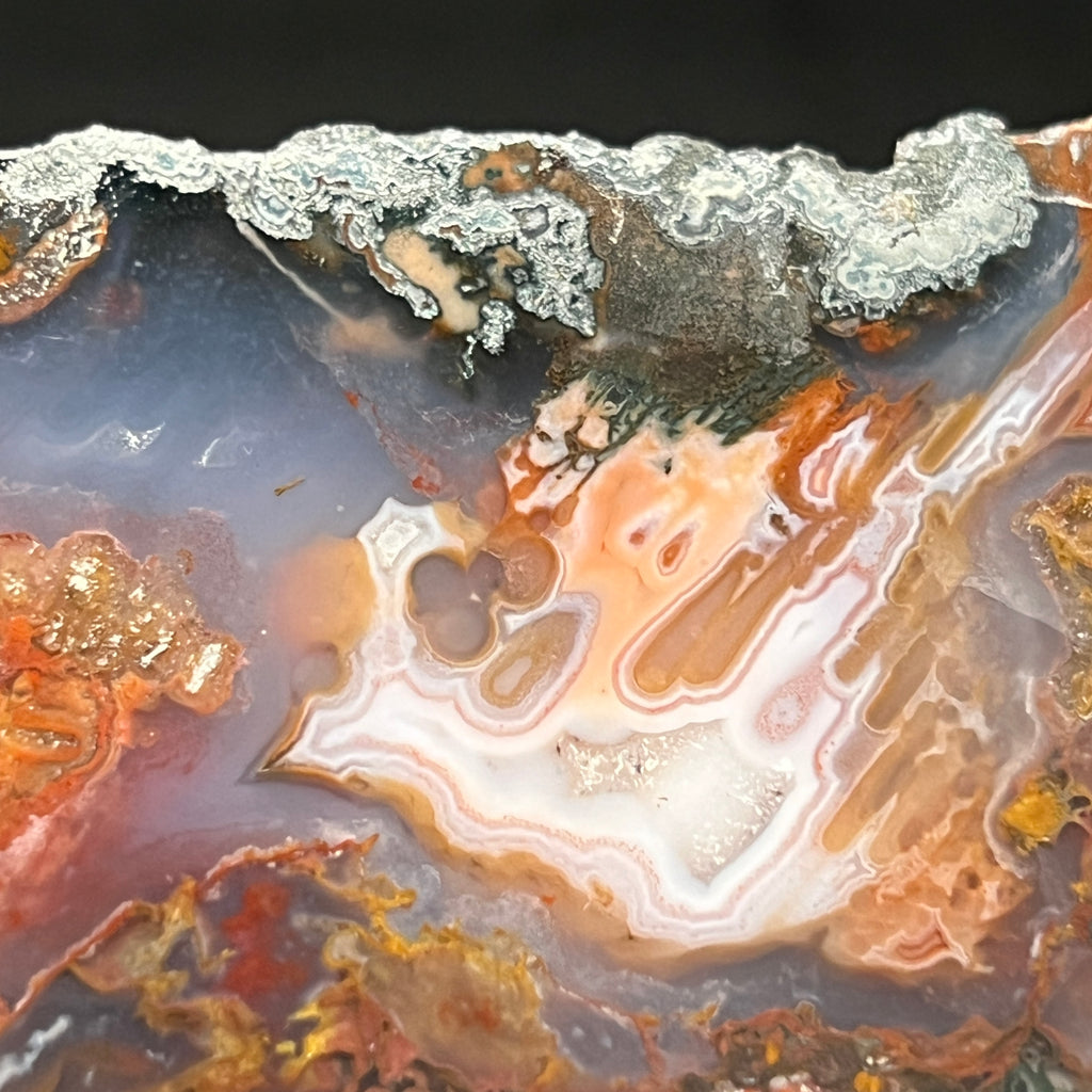 Shiny areas of polished hematite are evident near the edges of this agate showing a metallic gleam, especially when the specimen is turned in the light. 