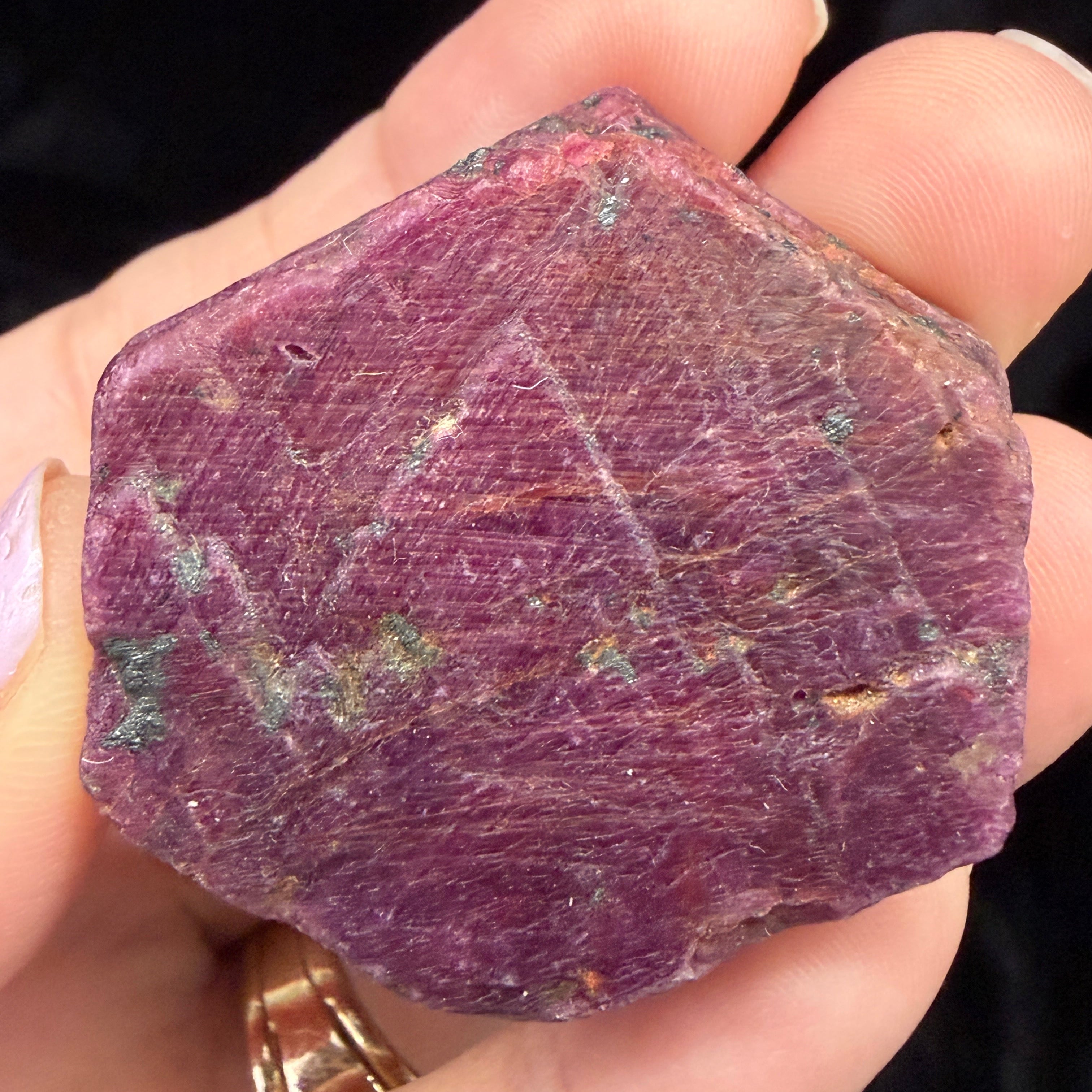Hexagonal Ruby crystal held in a hand against a dark background