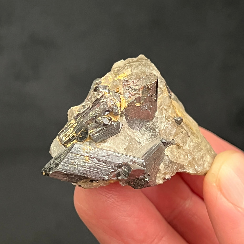 This is a terrific geniculate twin rutile! A geniculate twin crystal is one that presents with twinned form showing that the twin-plane has significantly changed the shape of the crystal. Also referenced in mineralogy as a "knee or elbow twin".