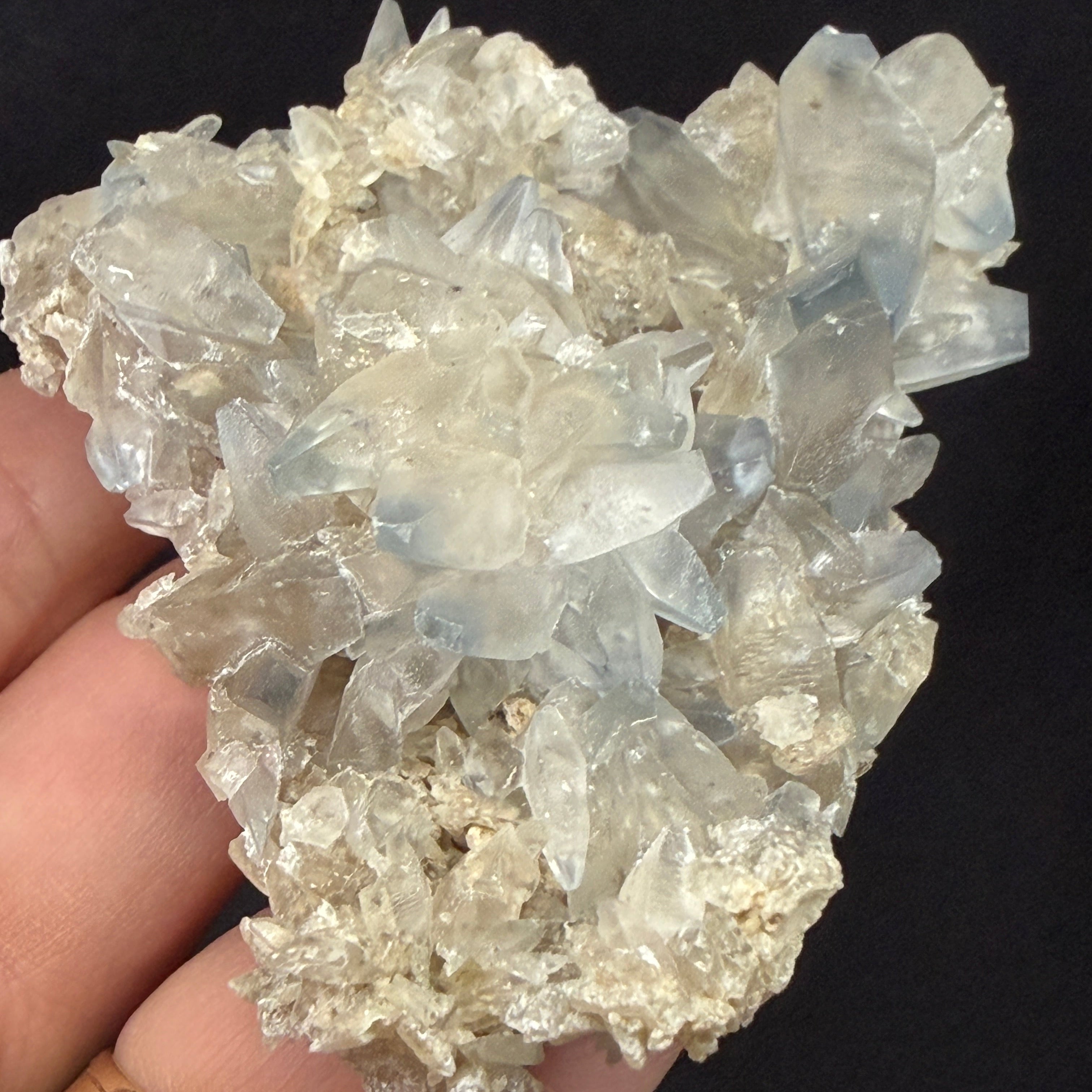 Hand holding a crystal cluster against a black background