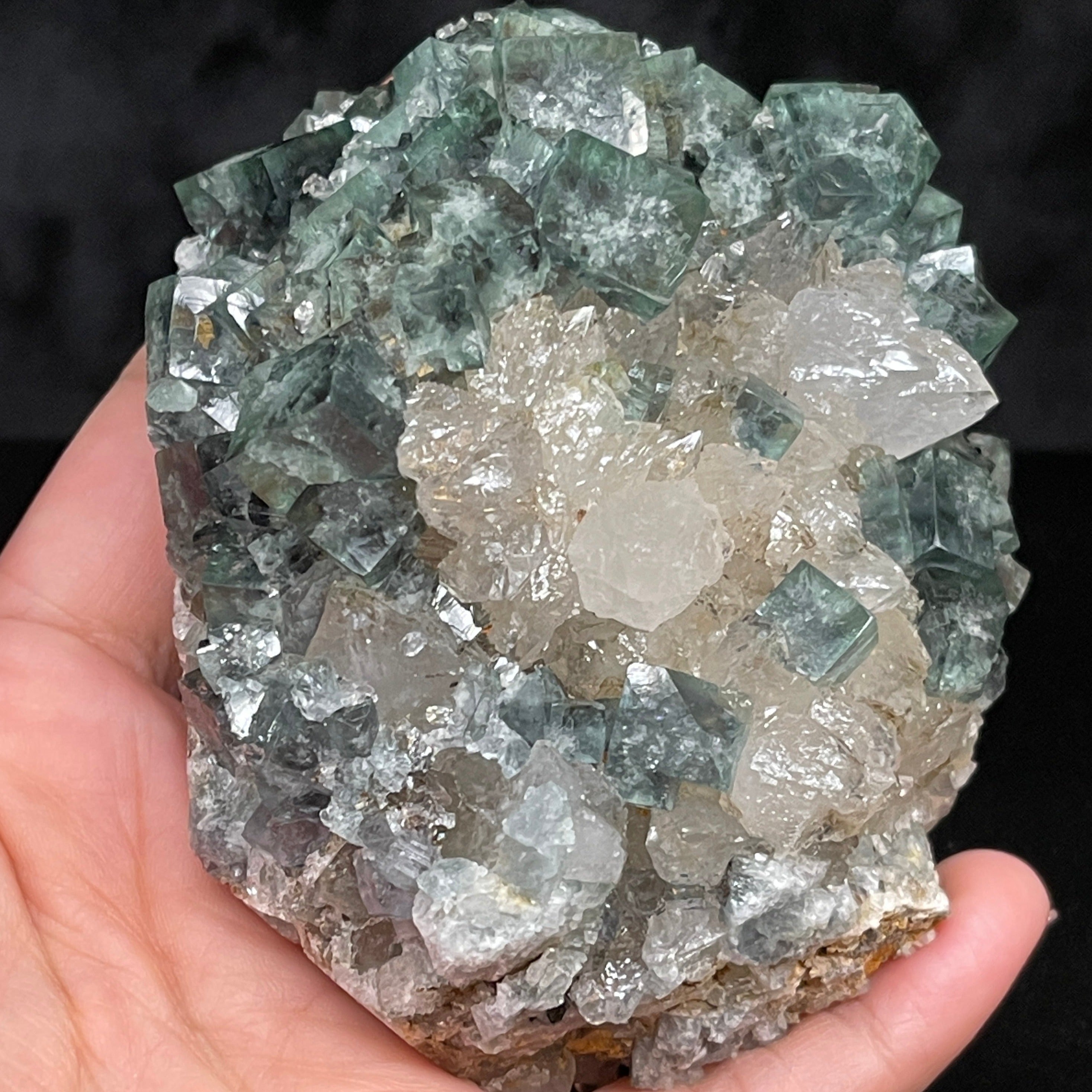 Supernova Fluorite cluster shown in hand inside lighting