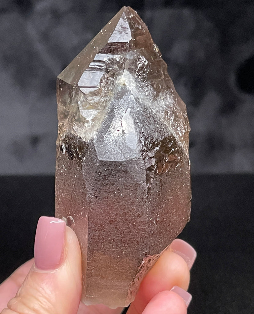 This is Smoky Quartz that exhibits some fascinating complexity in that it shows water clear secondary growth Quartz that grew on or over another darker, almost root beer colored Quartz crystal. 
